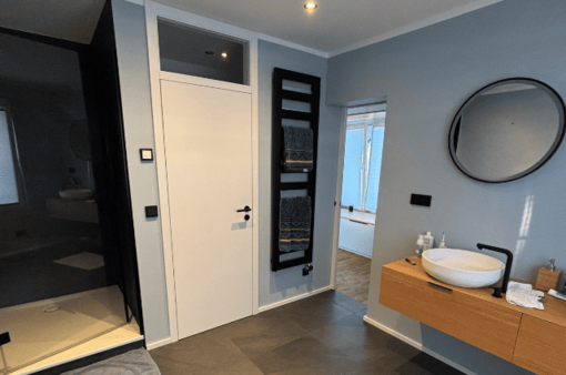 Nachher: modernes Bad Modernes Badezimmer mit Waschbecken, Wandspiegel und Zugang zur Dusche.