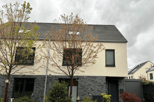 Vorher Moderne Wohnhausfassade mit großen Fenstern und Bäumen im Vordergrund. Wolkiger Himmel.