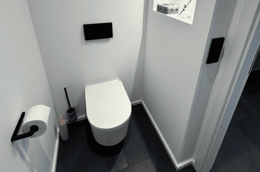 Nachher: modernes Badezimmer Modernes Badezimmer mit einer hängenden Toilette, Toilettenpapier und Putzutensilien.